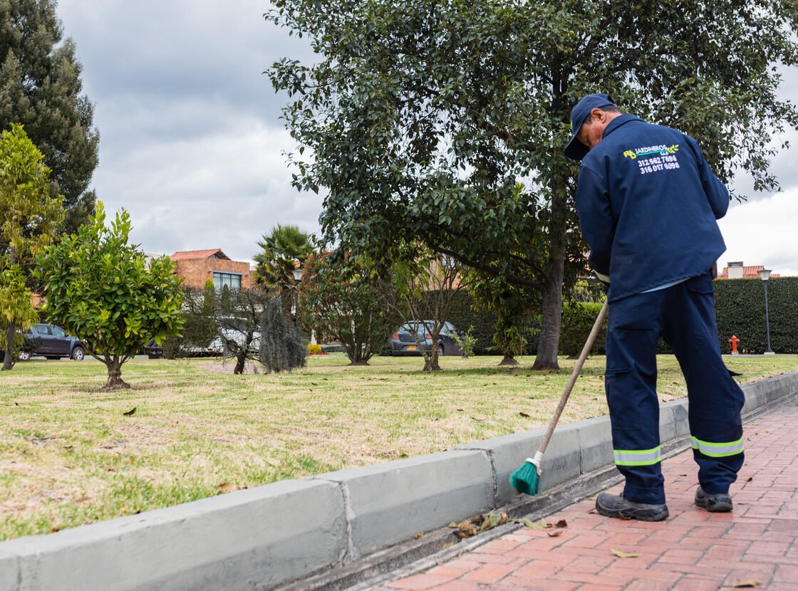 Operario de RYD barriendo el andén y el sardinel de una zona común exterior