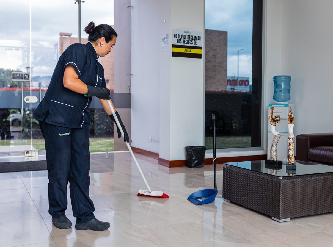 Auxiliar de aseo de RYD barriendo el piso de un lobby corporativo