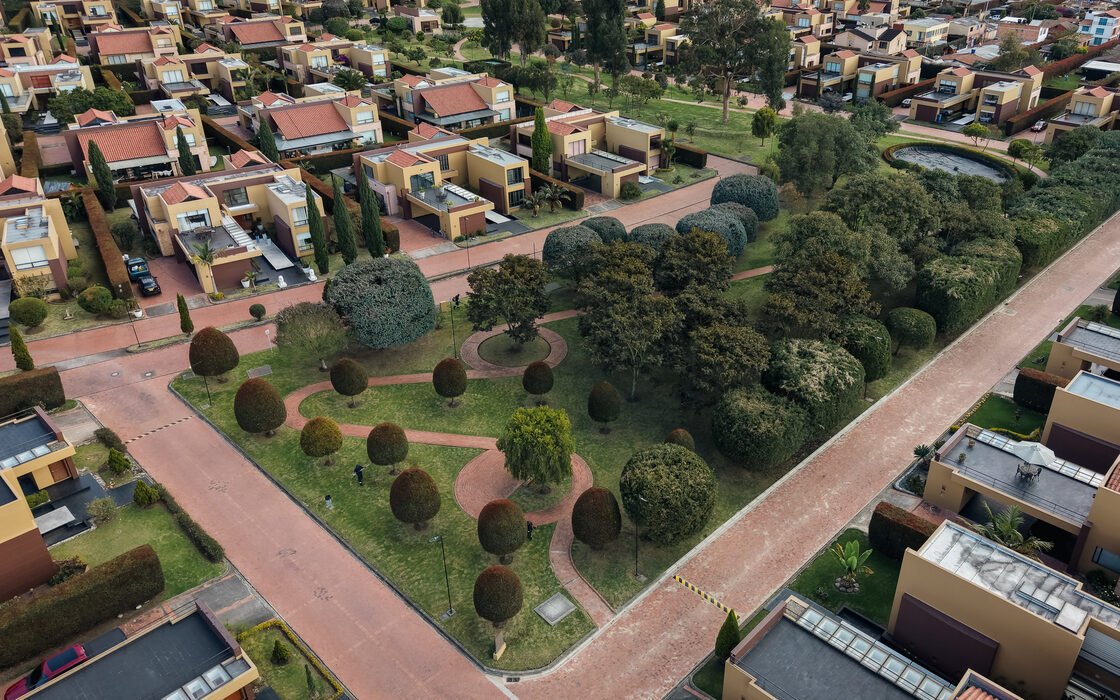 Vista aérea de un conjunto residencial con topiarios, senderos en ladrillo y zonas verdes