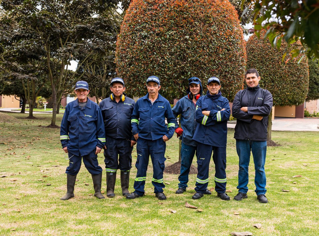 Grupo de siete jardineros de RYD frente a un topiario grande en una zona común