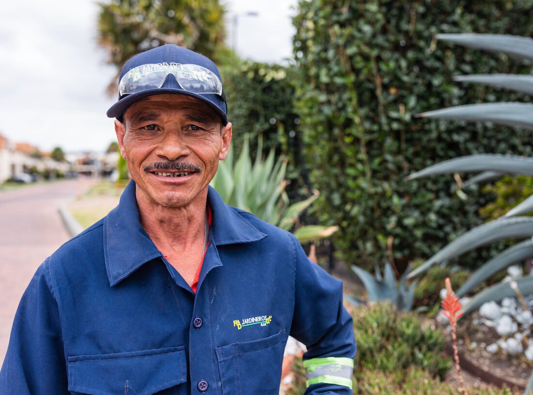 Retrato de un jardinero de RYD junto a un agave, con fondo de jardín desenfocado