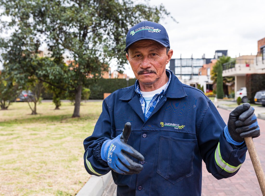 Jardinero de RYD levantando el pulgar, con guantes y herramienta en la mano