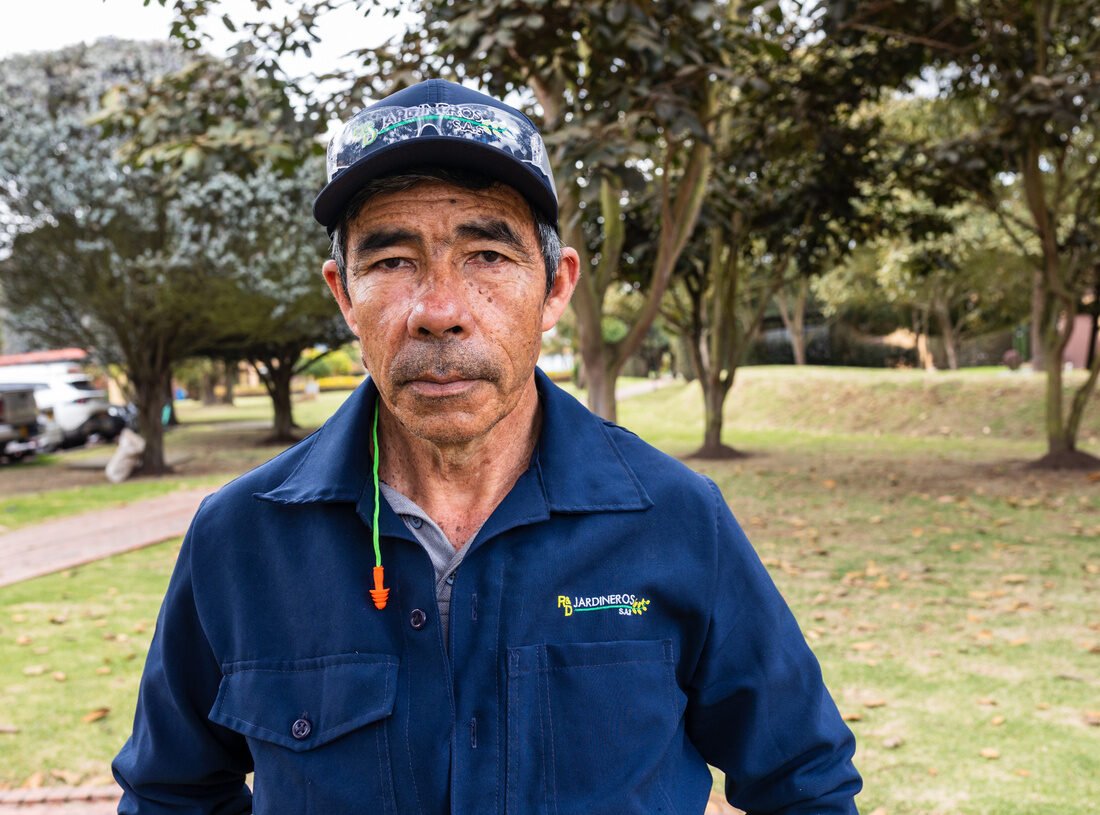 Retrato de un jardinero de RYD con overol y gorra de la empresa, en una zona común