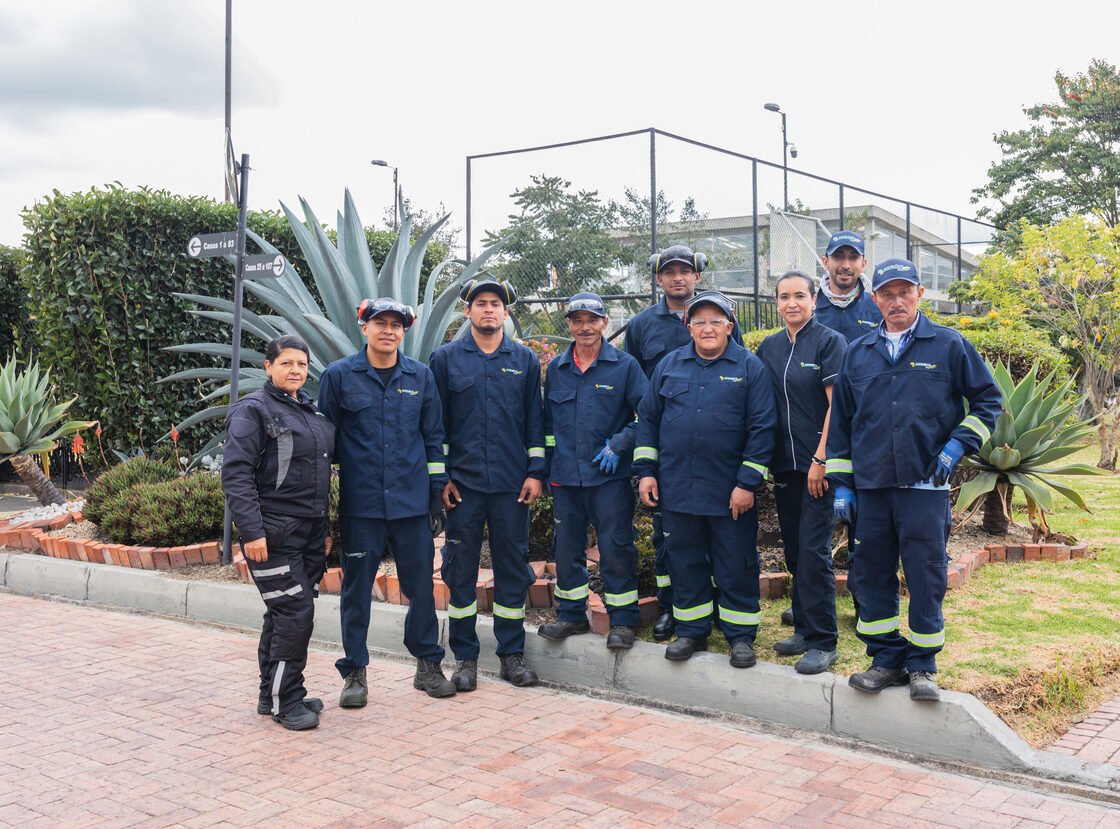 Cuadrilla completa de jardineros de RYD uniformada, de pie sobre un sendero en ladrillo junto a un agave