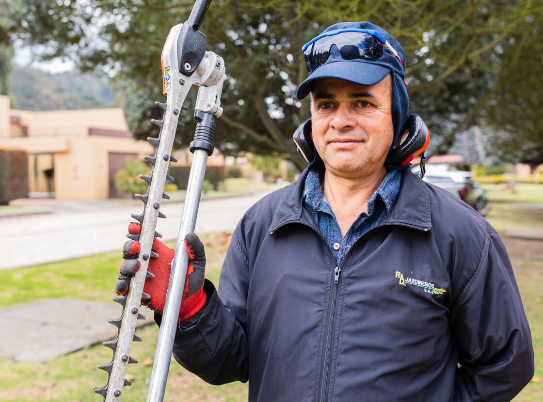 Retrato de un jardinero de RYD sosteniendo la podadora de setos, con casco y protección auditiva