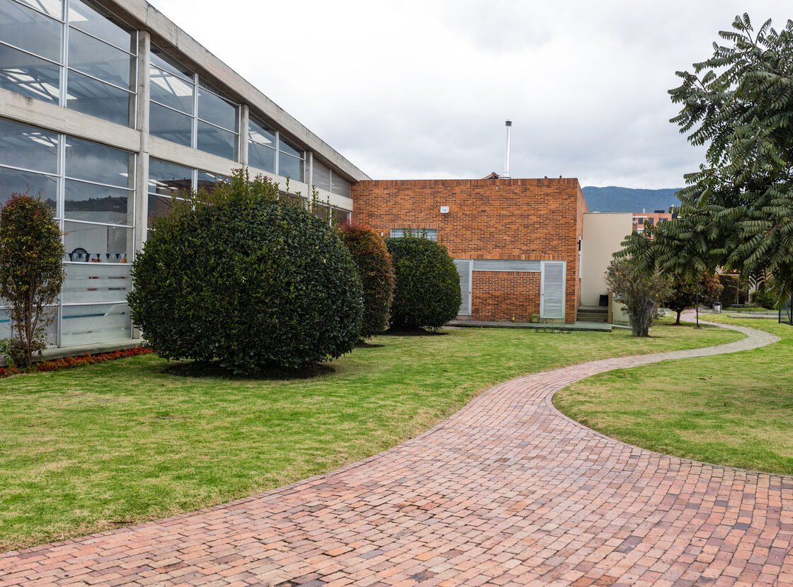 Sendero en ladrillo y arbustos podados en el jardín perimetral de una sede corporativa