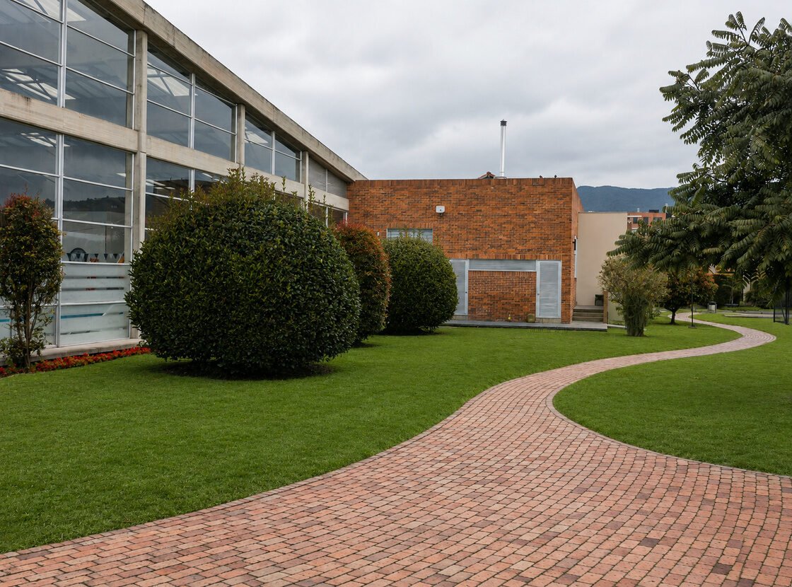 Sendero en ladrillo y arbustos podados en el jardín perimetral de una sede corporativa